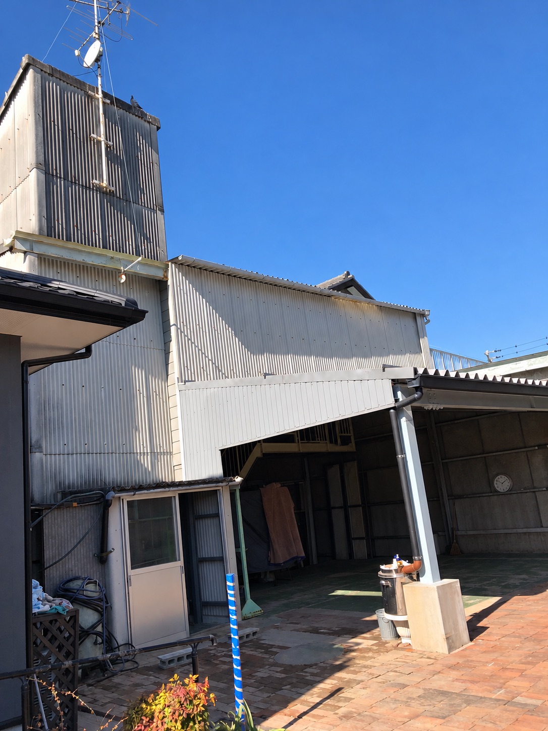 リノベ前の外観。淡い色の外壁と縦に高い部分、前面の屋根がある